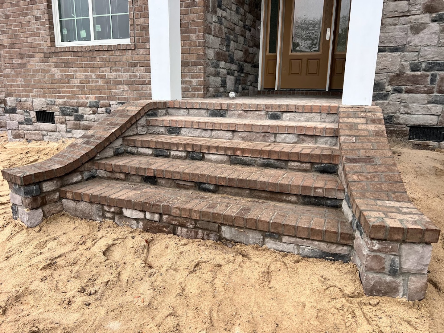 Curved brick entry steps and stone veneer on new construction home